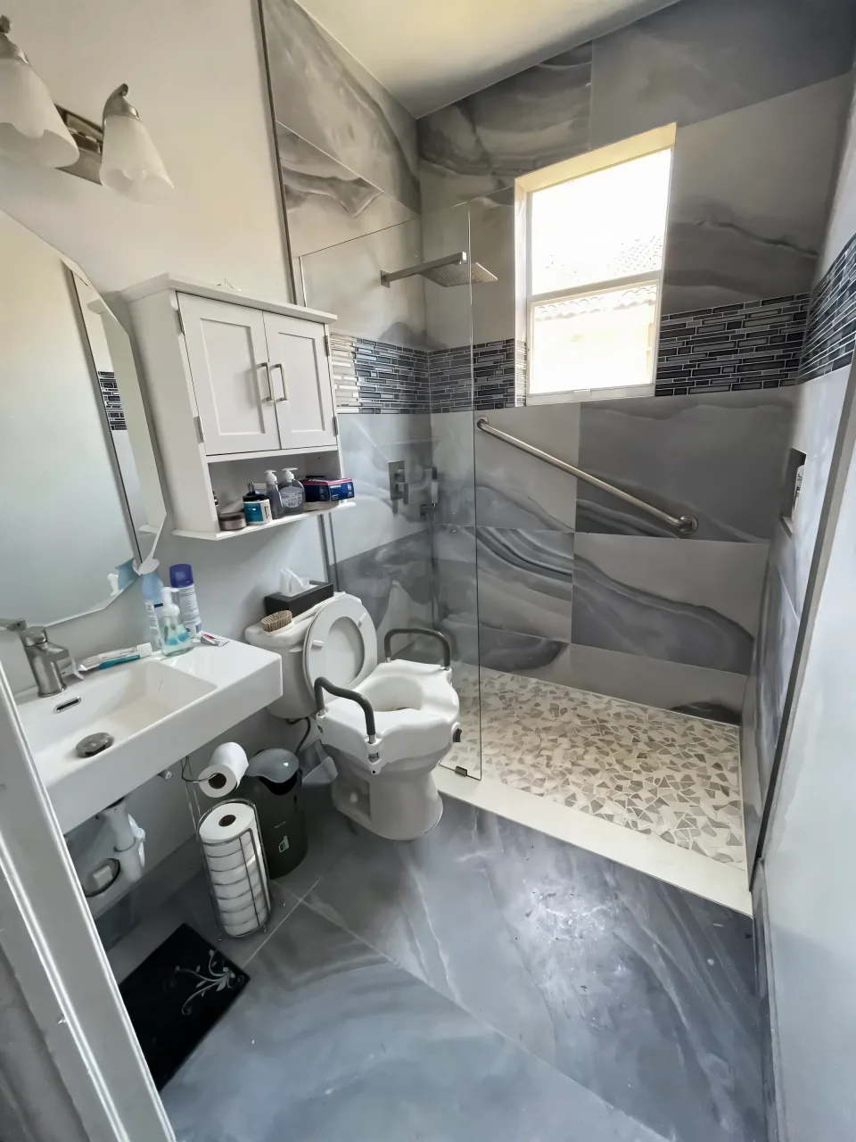 The same bathroom after conversion to a walk-in shower with a grab bar and a rainfall shower head