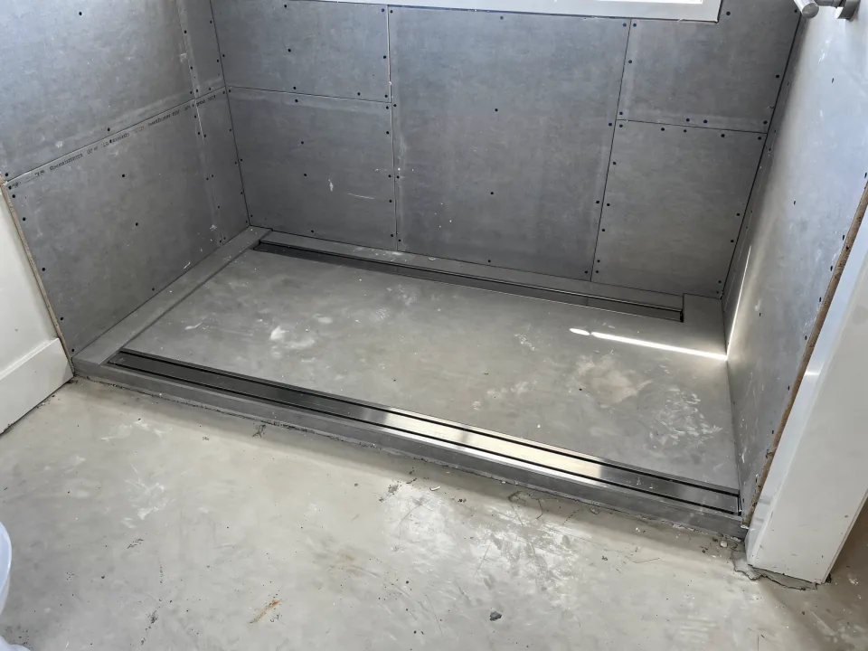 Zero-threshold shower entry under construction with a trench drain at the back wall and cement board walls