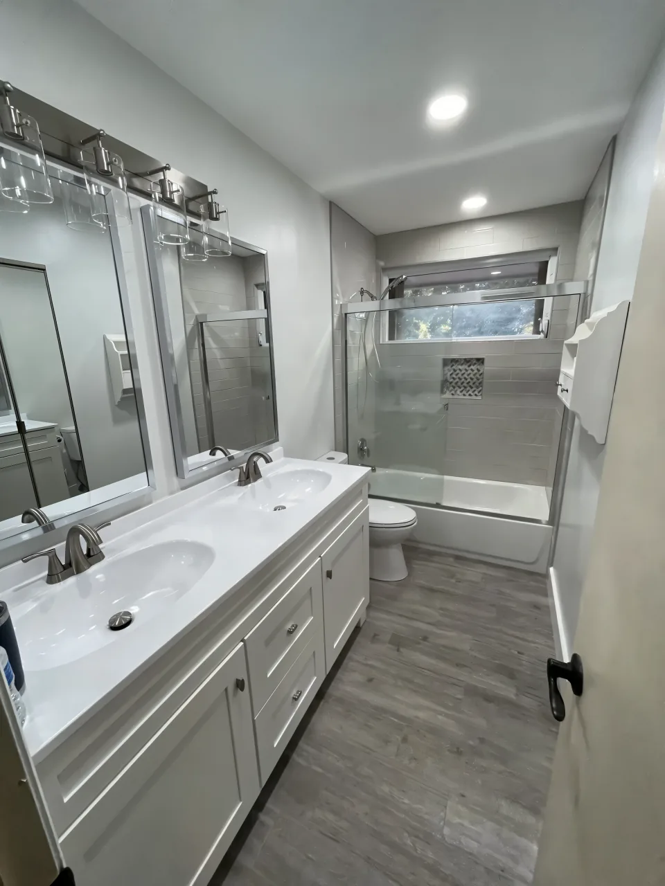 The same bathroom after the remodel with new tile, a new tub, a double vanity and a taller tiled shower
