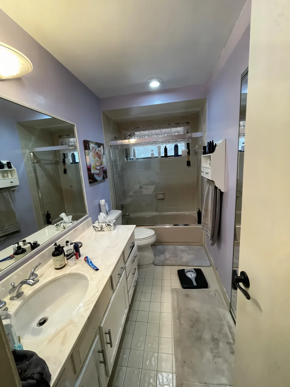 Bathroom before the remodel with an old tub-shower combo, dated tile and a dark vanity