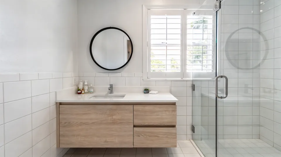 Finished bathroom with floor-to-ceiling white porcelain tile, a floating oak double vanity and a frameless glass shower