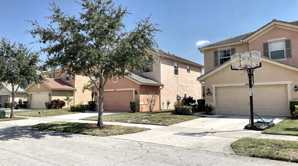 Pembroke Pines cul-de-sac with 1990s two-story stucco homes in sand and peach tones and young live oaks
