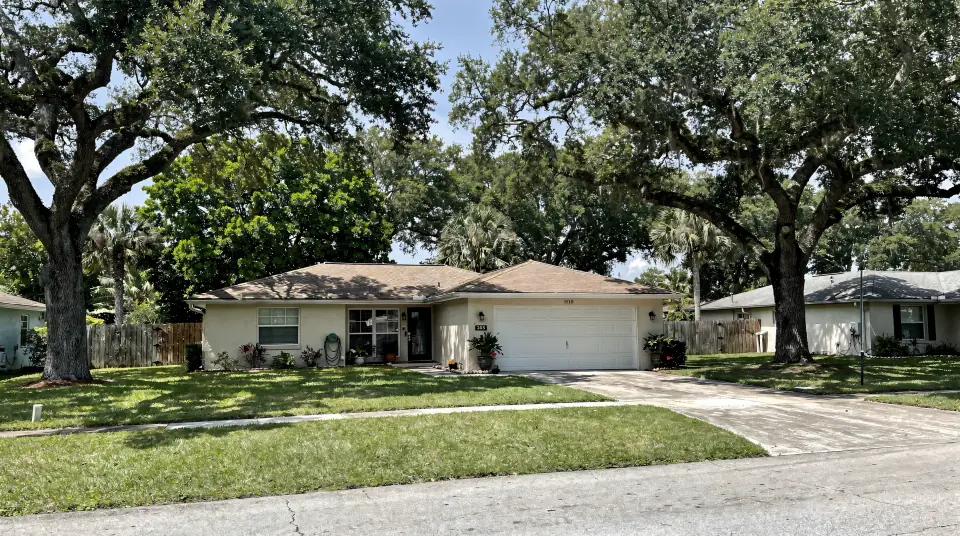 Tree-lined Plantation street with 1970s single-story homes under a live oak canopy
