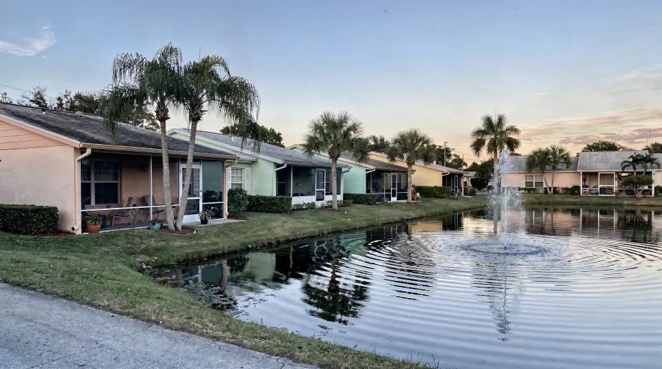 Sunrise neighborhood with low 1980s villas in pastel stucco, screened lanais and a lake with a fountain