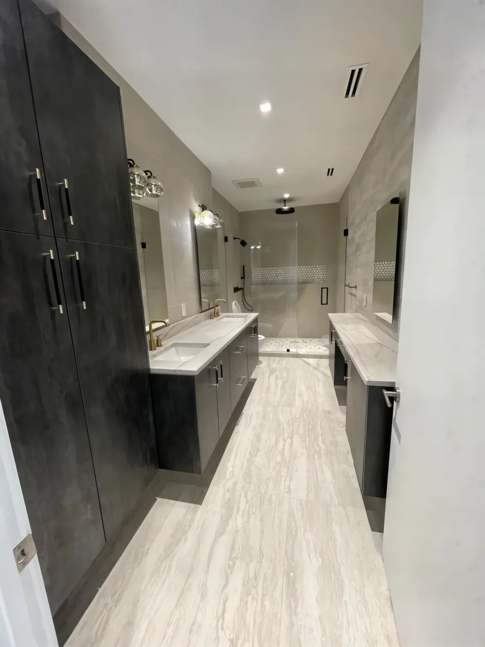 The same primary bathroom after the remodel with a floating double vanity and a glass walk-in shower