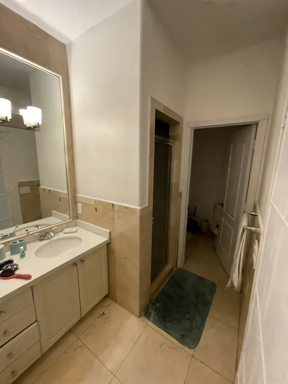 Closed-in 1990s primary bathroom with a builder-grade tub combo and a large vanity before the remodel