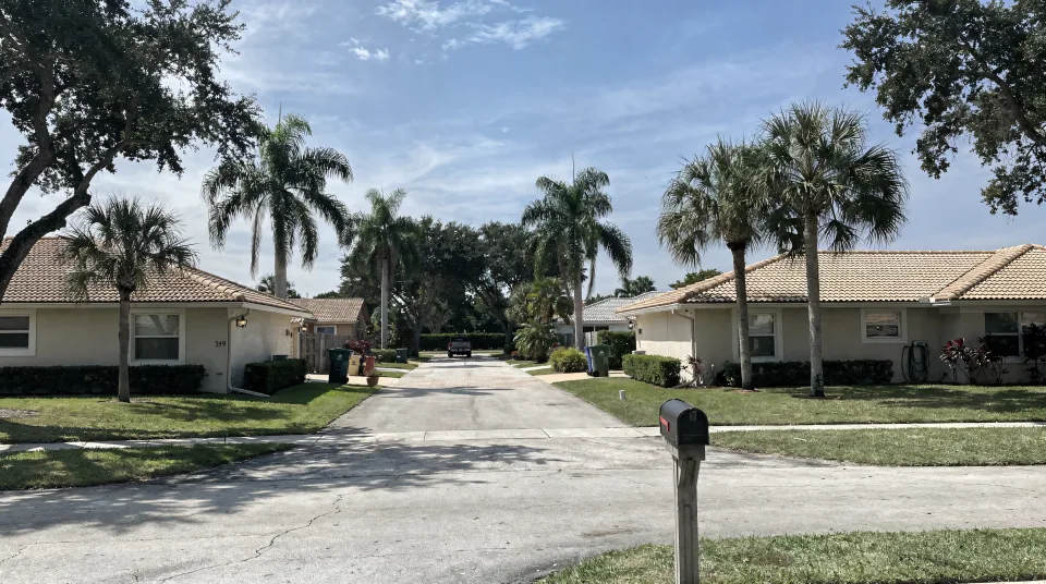 Quiet residential street in Broward County with single-story ranch houses, barrel-tile roofs and royal palms