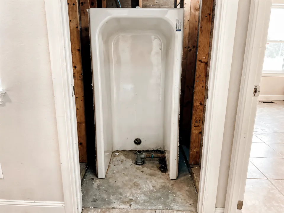 Old bathtub standing on edge in a hallway with the alcove stripped to bare studs