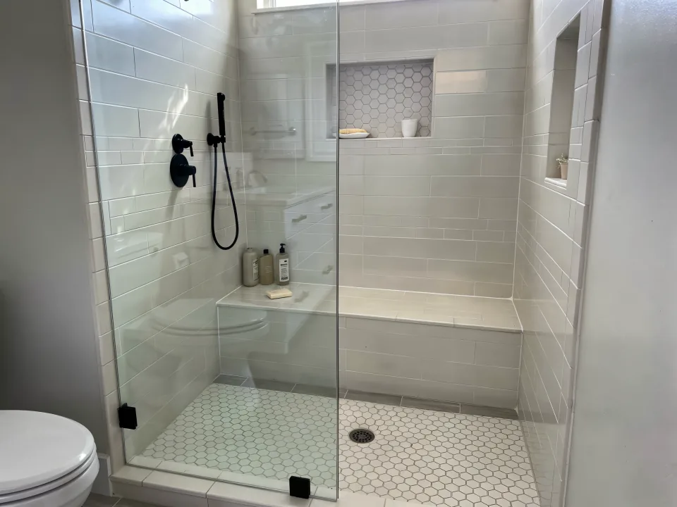 Finished low-threshold walk-in shower with a fixed glass panel, a tiled bench and a niche