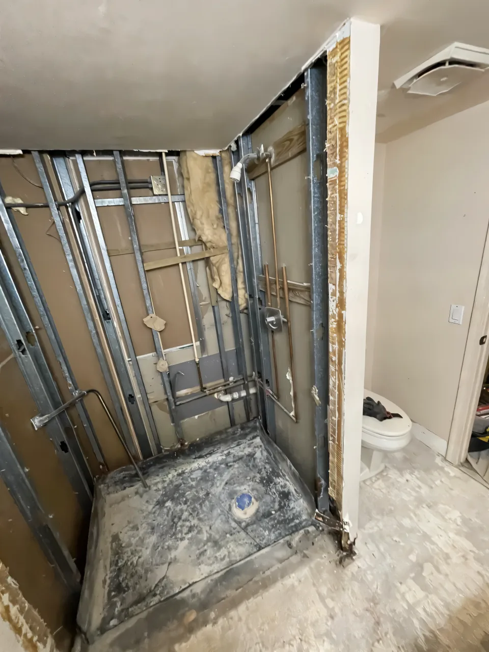Closed-in shower stall with a framed door and old tile before the work